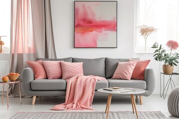 Grey sofa with pink pillows and blanket against white wall with abstract art poster.
