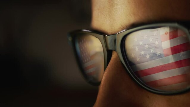 Cg footage with a reflection in glasses on a male face searching for information on the Internet and the USA flag
