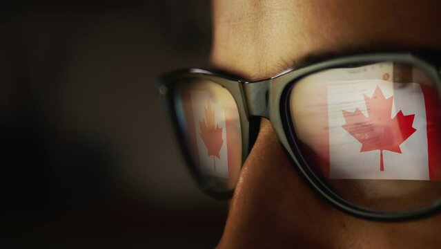 Cg footage with a reflection in glasses on a male face searching for information on the Internet and the flag of Canada.