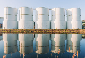 Oil supply. large white steel reservoirs of a tank farm for mineral oil at a canal