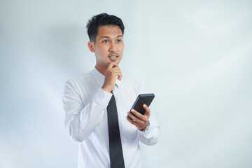 Adult Asian man thinking about something while holding mobile phone