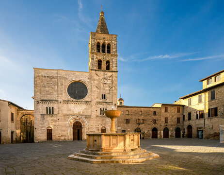 the medieval town square of Bevagna in Umbria, Italy , with the Church San Michele Arcangelo and the Public Fountain in the evening with the warm colors of a summer sunset 