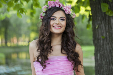 Happy young brunette woman with make-up, long wavy hairstyle, healthy clean skin and flowers outdoor - 759676740