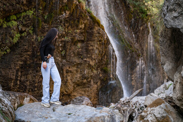 A woman explores new, fantastic places around the world. Female hiker crossing the waterfall.