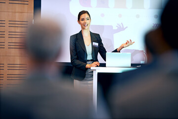 Business woman, talking and presentation with projector screen, conference or workshop with laptop for slideshow. Corporate training, seminar and speaker with info, audience and professional speech