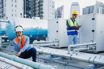 Asian man engineer using talkie walkie report working at rooftop building construction. Technician worker working checking hvac of office building. Engineering installing air conditioning system.