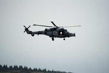Fototapeta na wymiar British army AgustaWestland AW159 Wildcat AH1 helicopter flying low over open countryside