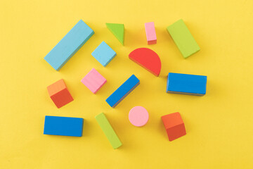 Colorful wooden toy blocks on yellow background
