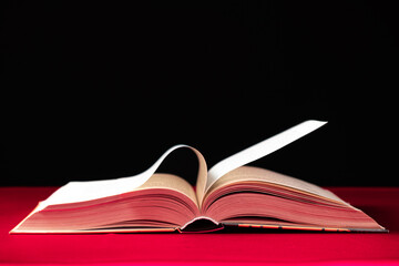 Pages of a thick book are turned on a pink and black background, space for text.