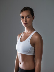 Woman, serious in portrait and confident for fitness, strong and determined with sweat from workout on grey background. Body, endurance and athlete for sports, exercise with pride and power in studio