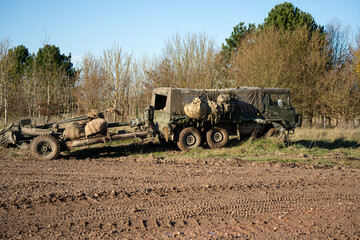 British army bae systems, Puch, Daimler, Pinzgauer High-Mobility All-Terrain 6x6 vehicle towing a 105mm Light Artillery Gun on a military exercise © Martin