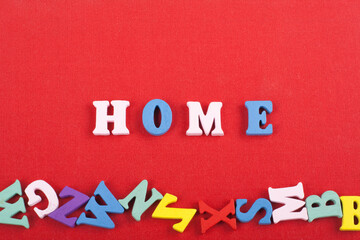 HOME word on red background composed from colorful abc alphabet block wooden letters, copy space...