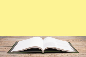 open book. Composition with hardback books, fanned pages on wooden deck table and yellow background. Books stacking. Back to school. Copy Space. Education background.