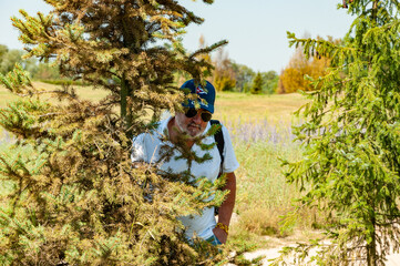 Senior old Hispanic man in summer style with Cuban cap outdoor hiding in spring nature park