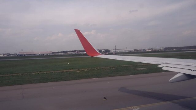  The plane's wing stands stark against the runway, bracing as the final stretch speeds towards lift-off.