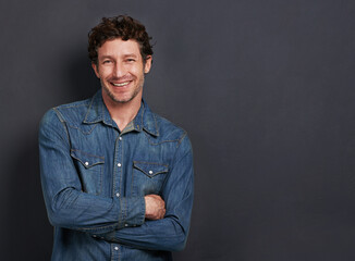 Obraz premium Studio, portrait and man with confidence, casual fashion and mockup space for creative professional. Relax, happy and face of person with smile, pride and trendy denim style on dark grey background