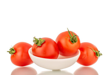 Several ripe cherry tomatoes with white ceramic plate, macro, isolated on white background.