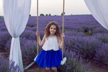 Adorable preschool girl in white blouse stand in bloom lavender field outdoor over sunset nature...