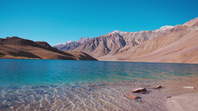 lake in the mountains. 4K shot of blue clear water of Chandra Taal Lake against Himalaya mountains at Spiti Valley, Himachal Pradesh, India. Beautiful Chandratal during sunny summer day. 