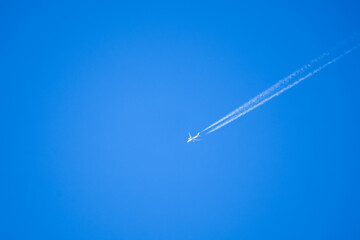 high altitude twin engine contrails (jet airplane vapour trails) across a deep blue clear sky