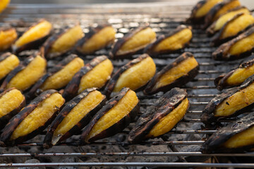 Bananas are being grilled on a charcoal grill. Let it cook slowly, street food in Thailand, Grilled bananas are a sweet and delicious dessert