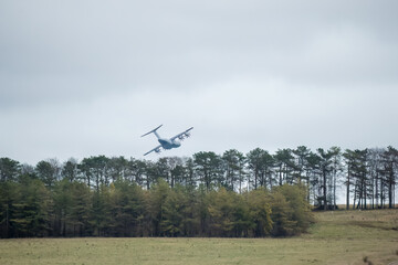 RAF Royal Air Force Airbus A400M Atlas military cargo plane, flying low, skimming treetops on a...