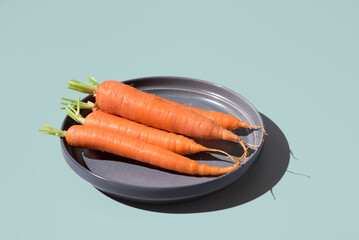 Zanahorias frescas crudas en un plato gris sobre fondo verde. Vista superior	