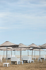 Sandy beach and beach umbrellas. White deck chairs in the form of stacks. Beach holidays