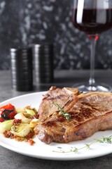 Delicious fried beef meat and vegetables on grey table