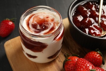 Tasty yoghurt with jam and strawberries on black table, closeup