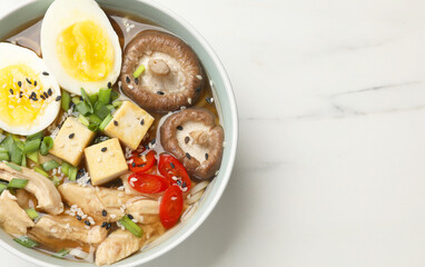 Bowl of delicious ramen on white marble table, top view with space for text. Noodle soup