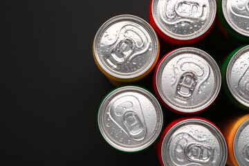 Energy drinks in wet cans on dark background, top view. Space for text