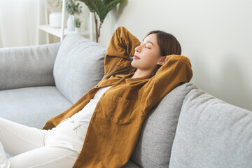 Relaxed serene, happy calm attractive asian young woman peace of mind, relaxing on comfortable sofa, rest in cozy home modern living room, breathing fresh air and eyes closed, dreaming enjoy wellbeing - obrazy, fototapety, plakaty