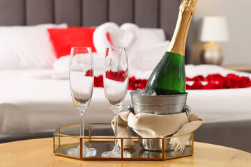 Honeymoon. Sparkling wine and glasses on wooden table in room