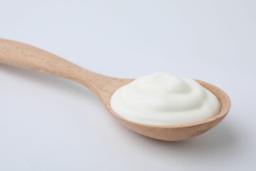 Delicious natural yogurt in spoon on light background