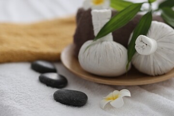 Fototapeta na wymiar Spa stones, flowers and herbal bags on towel indoors, closeup
