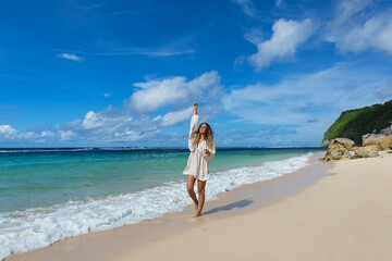 Fototapeta na wymiar Beautiful young woman walking barefoot on the beach