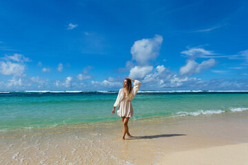 Beautiful young woman walking barefoot on the beach
