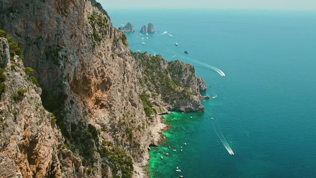 Stunning aerial view of Capri Island with rugged coastline and azure Tyrrhenian Sea in Italy. Faraglioni stacks in the distance.