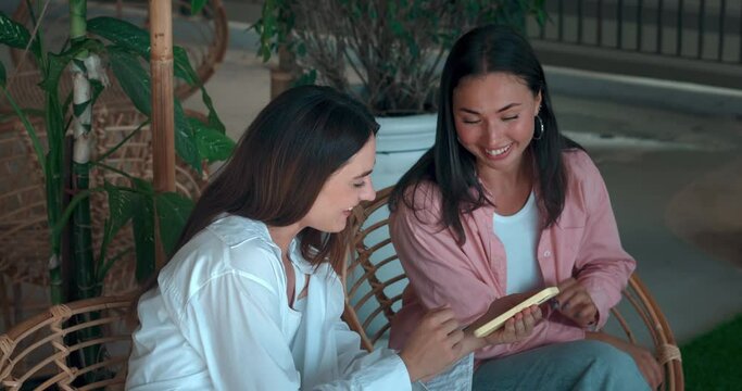 Young women sitting bench engaged conversation phone hand showcasing trust friendship. Trust friendship laughter smiles Trust friendship foundation joyful life Embracing positivity shared experiences.