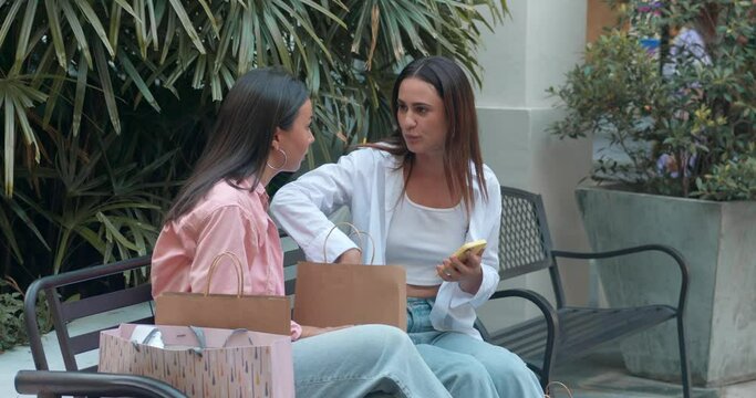 Two women friends sitting bench close-up chatting using phones embodying women's friendship. Women's friendship shines smiles laughter Women's friendship blend joy sincerity connection.