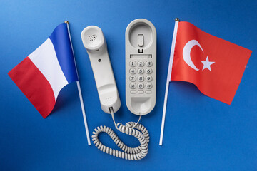 Flag of France, Turkey and old corded telephone on a blue background, concept on the theme of...