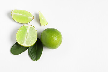 Fresh ripe limes and leaves on white background, flat lay. Space for text