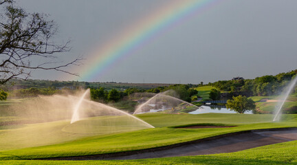 A lush golf course with a rainbow overhead.  Photographed in South Africa.