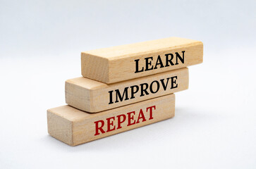 Learn, Improve and Repeat text on wooden blocks with white cover background. Improvement and...