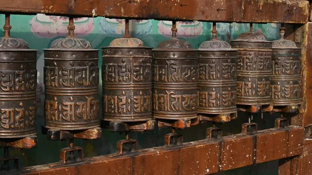 Rows of bronze prayer wheel in Buddhist temple in Kathmandu city of Nepal. The words mantra "Om Mani Padme Hum" is written in Sanskrit on the outside of the wheel.