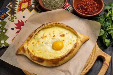 Traditional georgian khachapuri with egg yolk on wooden background