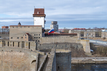 Russian flag in the Ivangorod fortress against the background of Hermann's Castle (Narva, Estonia) on a March day. Border between Russia and Estonia - 759850733