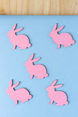 set of pink rabbits made of wood on the surface of a blue book set on a wooden ground