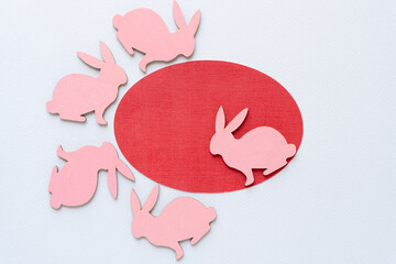 red paper oval and five pink wooden bunny shapes
